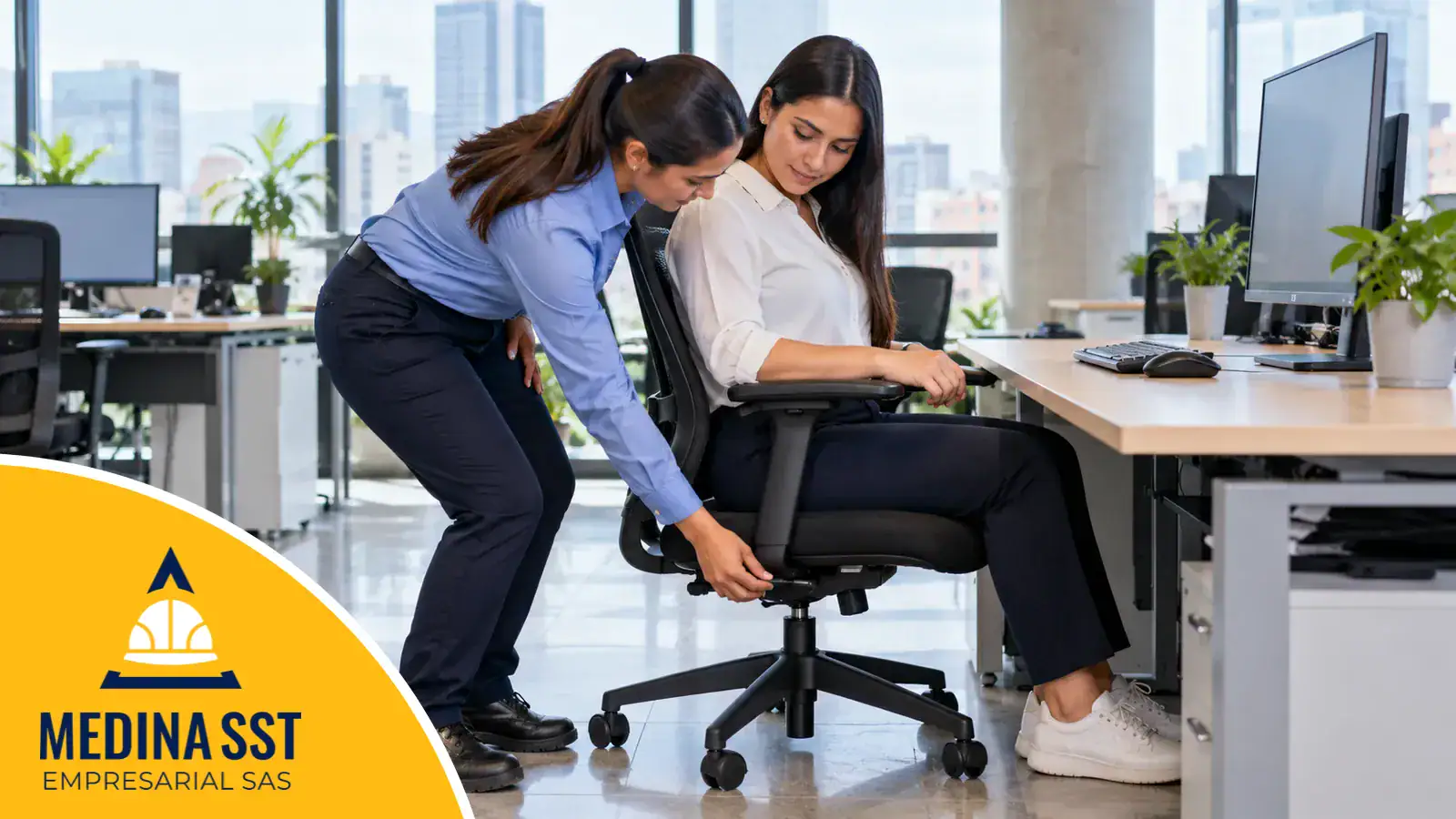 Una profesional de seguridad y salud en el trabajo ayuda a una trabajadora a ajustar la altura de su silla frente a un escritorio con monitor en una oficina luminosa