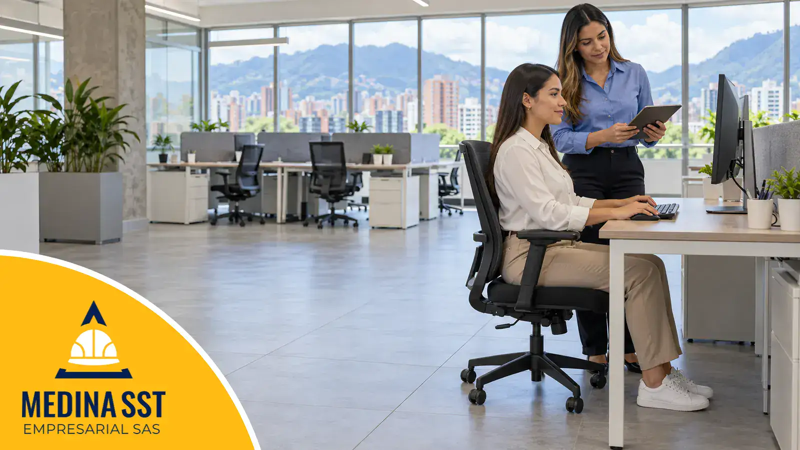 Ergonomía en la oficina: una trabajadora sentada en una silla ergonómica con los pies apoyados y el monitor de frente mientras una profesional de seguridad y salud en el trabajo revisa su puesto con una tableta