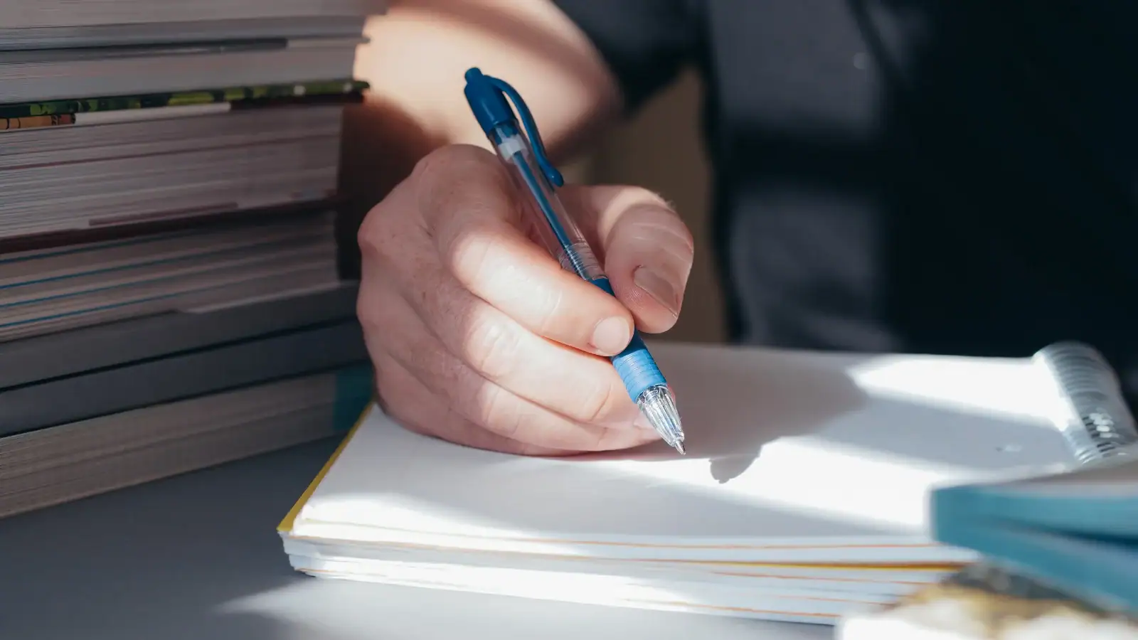 A hand holding a pen with a non-dominant hand, demonstrating the practice of strengthening neural connections