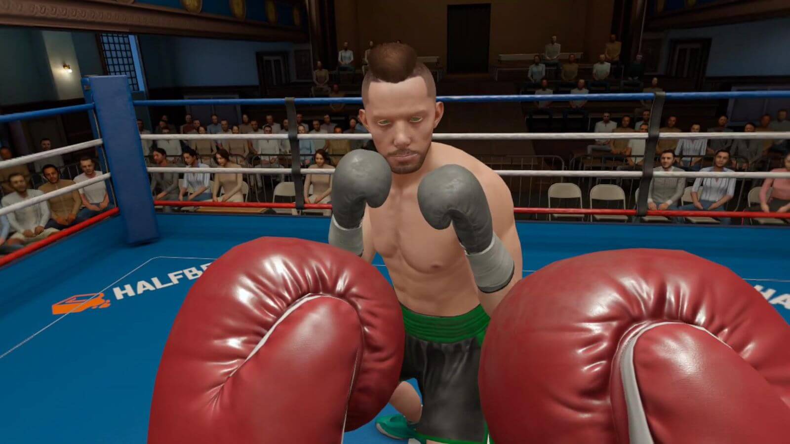 Players red boxing gloves up at half guard as opponent closes in. Crowd watch on from outside of the ring