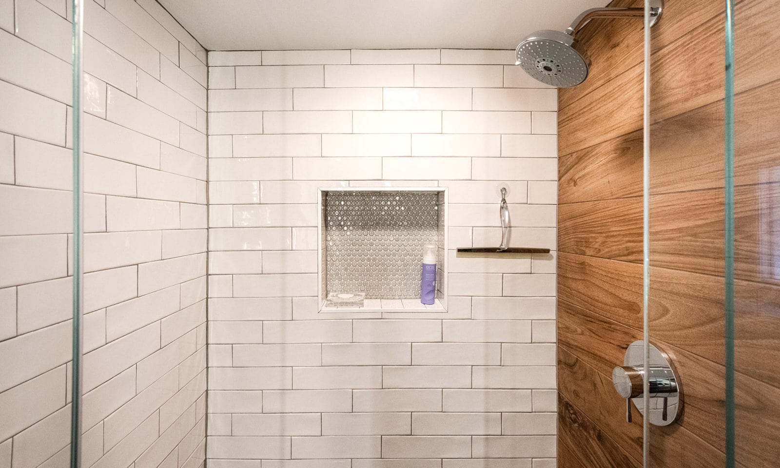 view of shower with white subway tile and wood looking tile