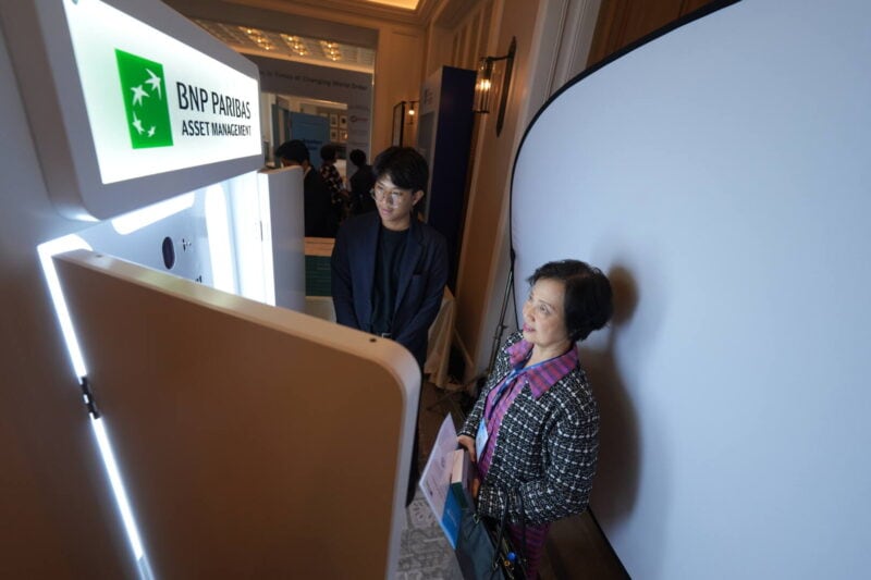 Guest posing in front of a white backdrop while the newspaper photo booth takes her picture at a corporate event
