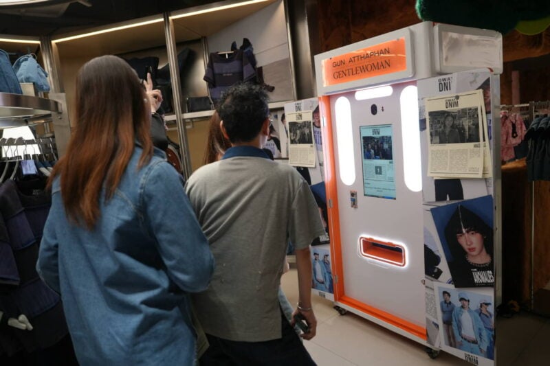 Two guests watching the screen of a branded newspaper photo booth at a retail event