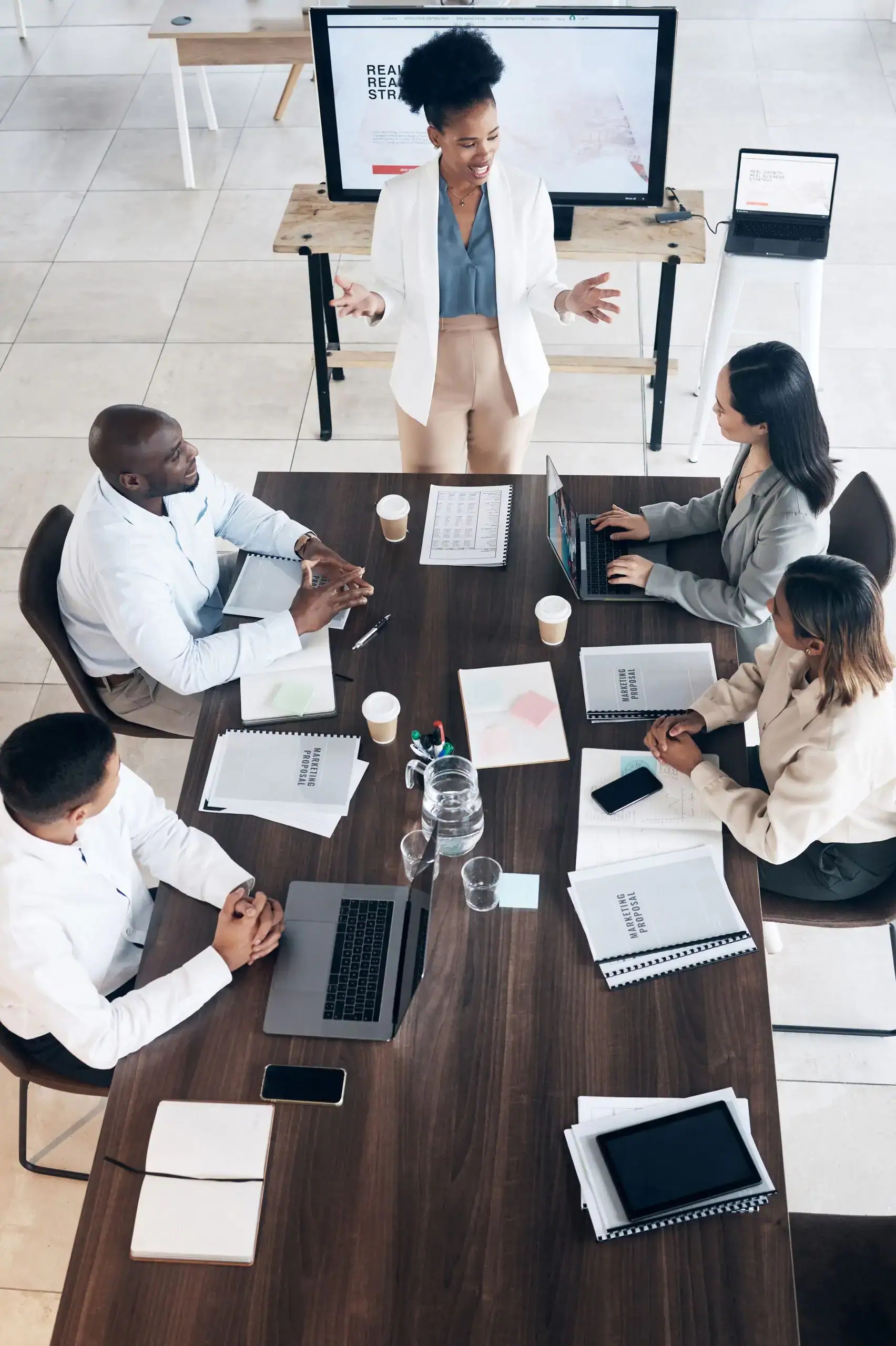 Overhead view of a woman leading a business meeting with four colleagues at a conference table.