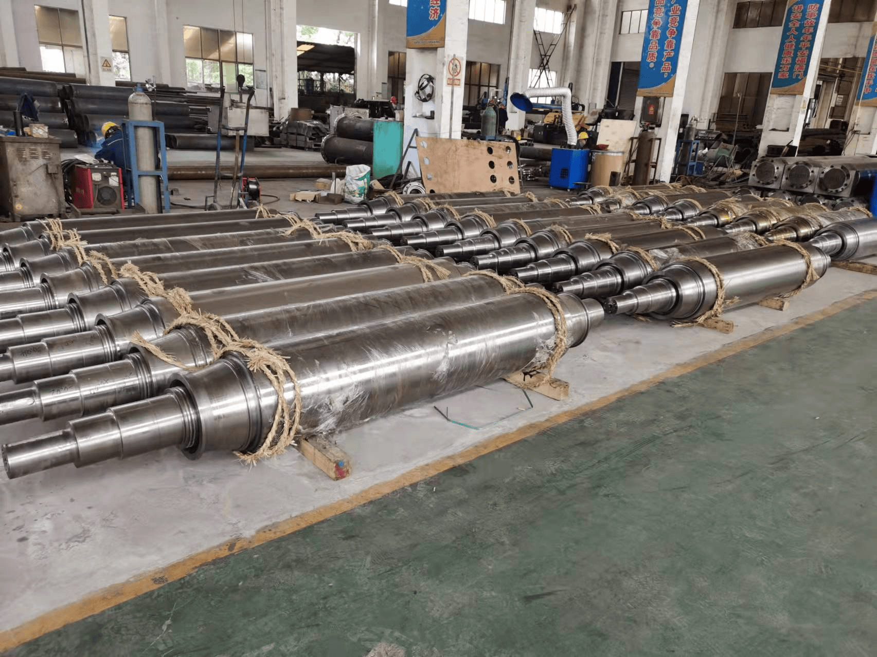 Finished cylindrical furnace roll assemblies with shaft ends laid out in the workshop
