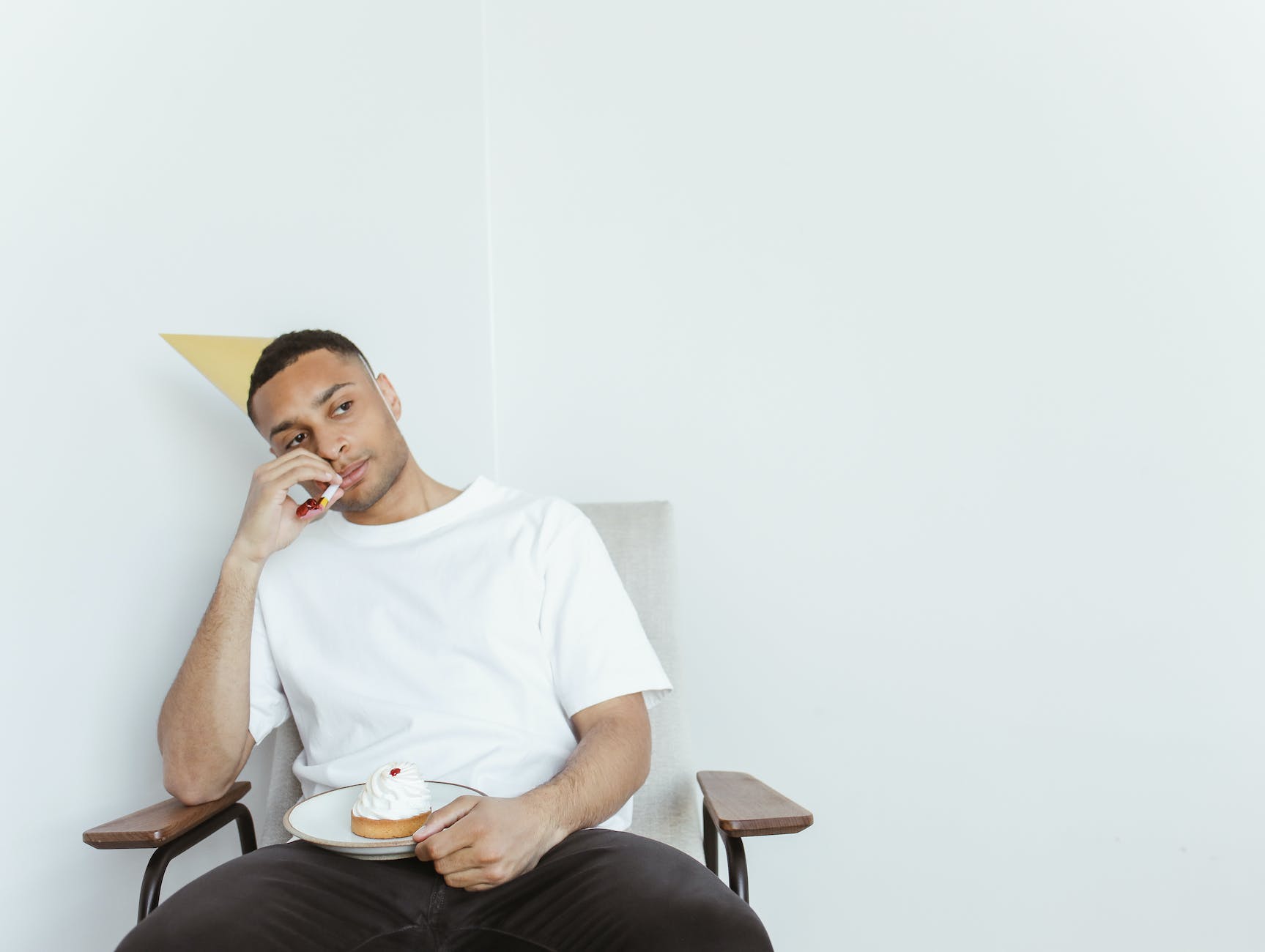 a man wearing a party hat holding a piece of birthday cake