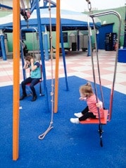 picture of a toddler and a girl on a swing outside with a pulley system