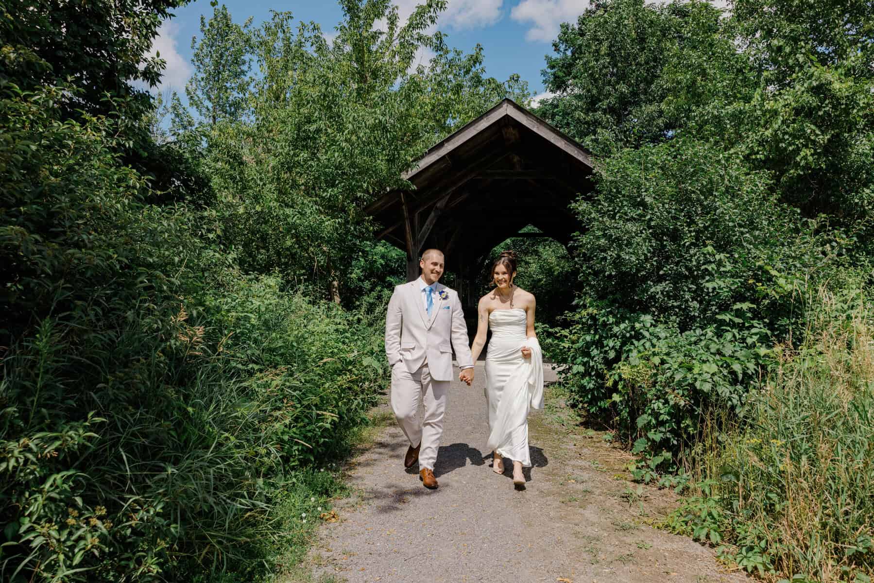 Sophie and Josh walk together on a tree-lined path after their first look