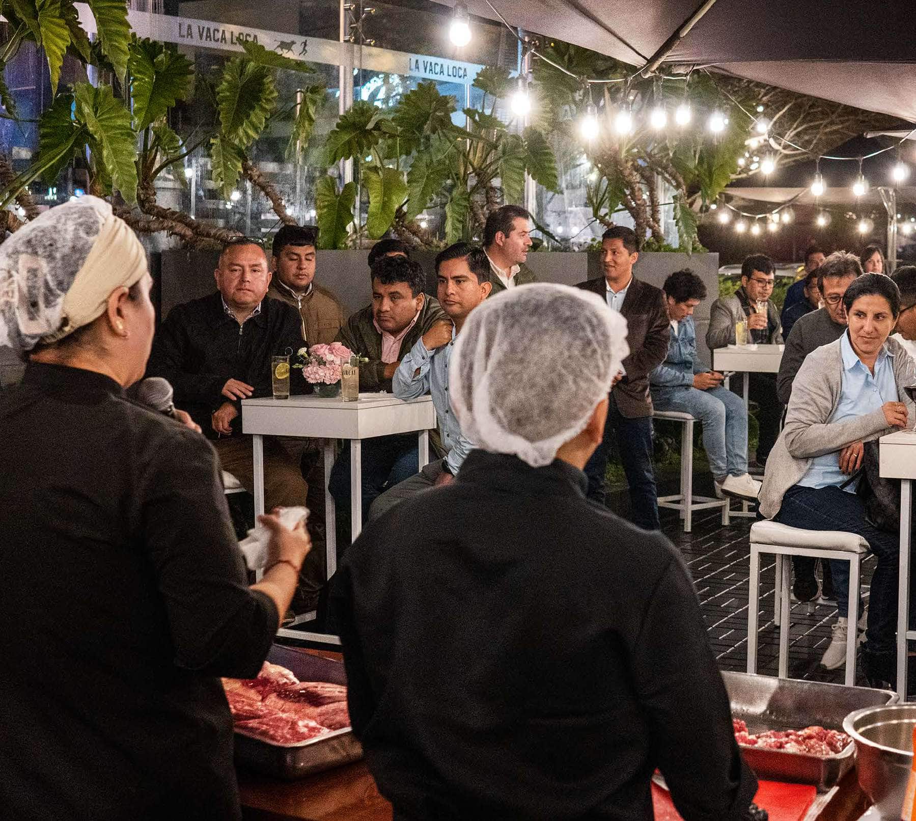 Staff de cocina presentando cortes de carne cruda a un grupo corporativo en la terraza de La Vaca Loca