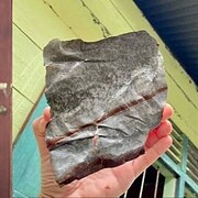 Josua segurando o meteorito e pedaço do telhado de zinco arrancado na queda - Divulgação/Facebook/Josua Hutagalung