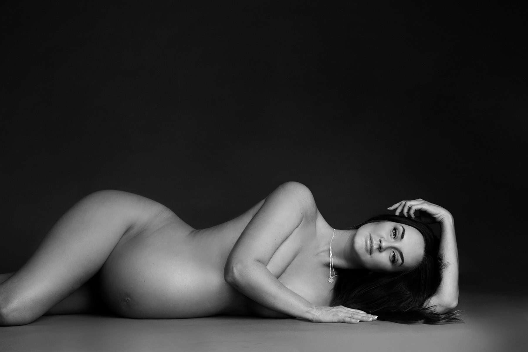 Elegante gravidfotografering av en nybakt mor, portrett av gravid kvinne med naturlig uttrykk, svart-hvitt fotografi som fokuserer på skjønnheten i svangerskapet, profesjonell gravidfoto service.