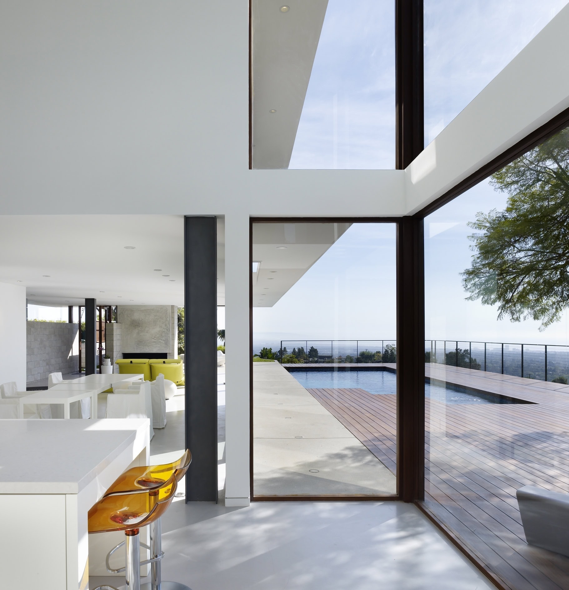 Contemporary residential interior with open floor plan and panoramic views through large glass windows.