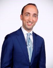 Business professional in formal suit smiling at the camera.