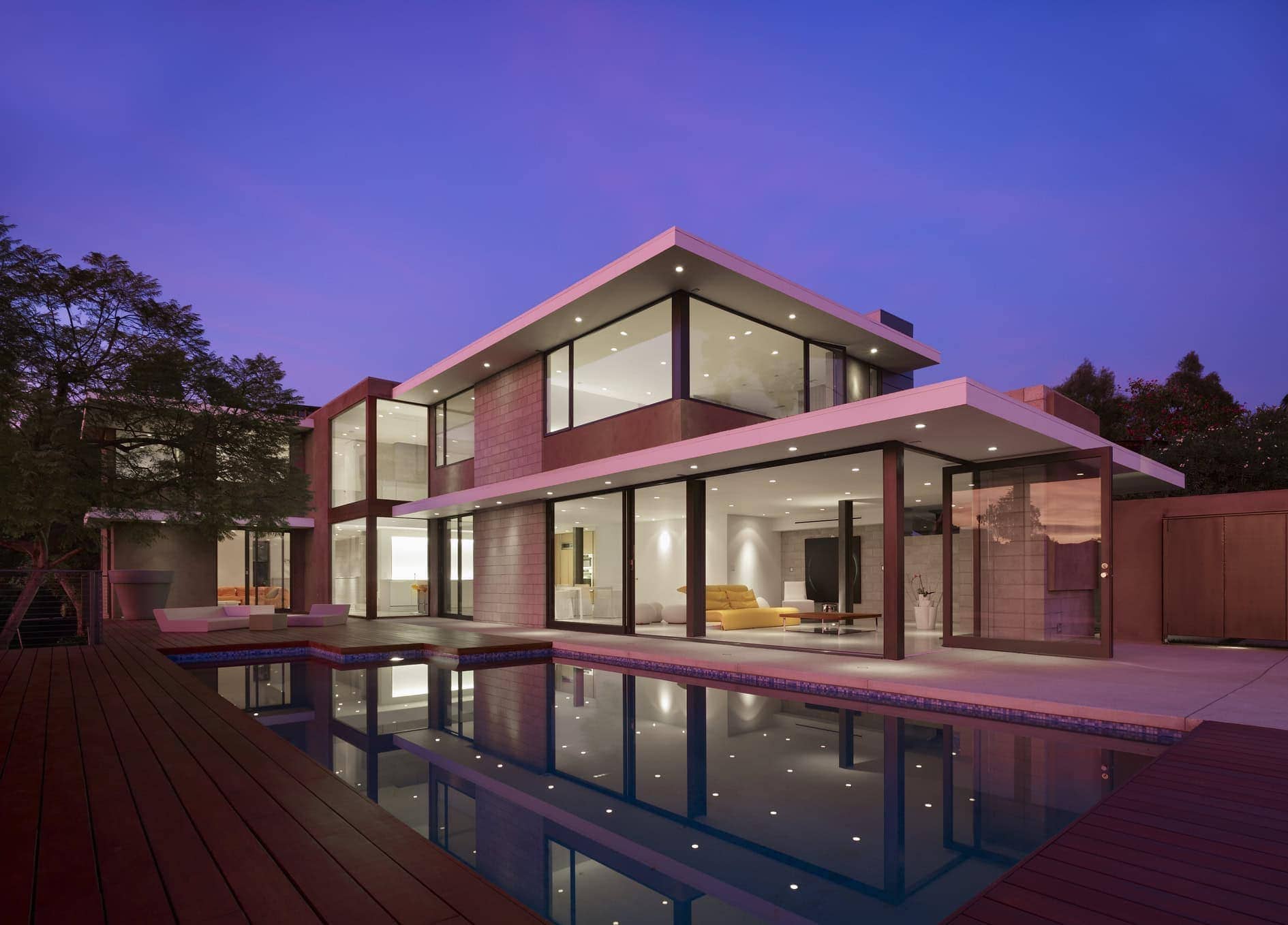 Modern residential home featuring sleek architecture and large glass windows at dusk.