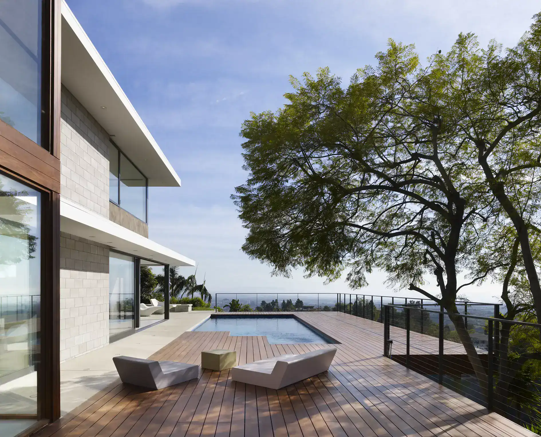 Modern house exterior with a pool and wooden deck, featuring clean lines, large glass windows, and minimalist furniture.