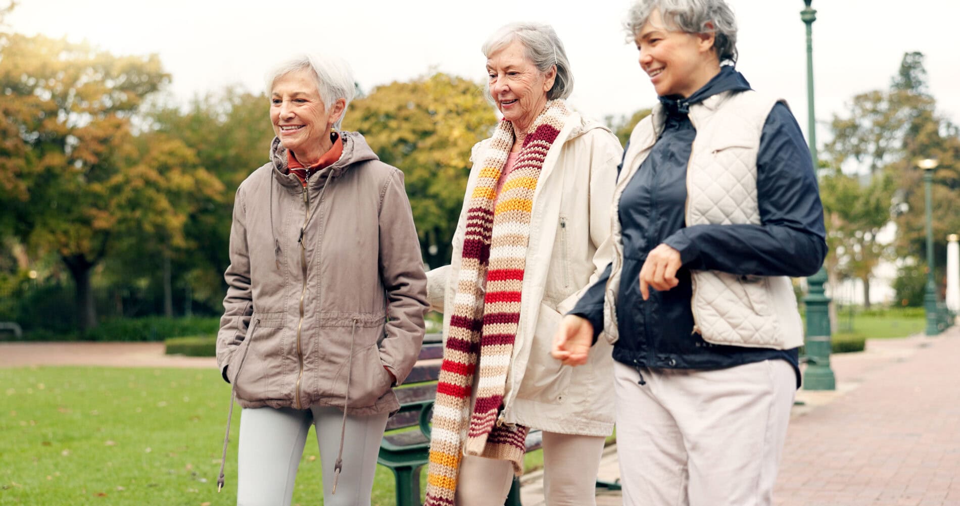 Three senior women walking in a park
