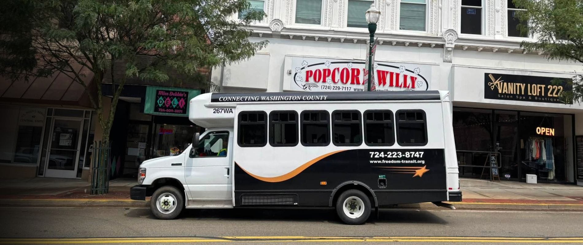 White, orange, and black bus parked on city block