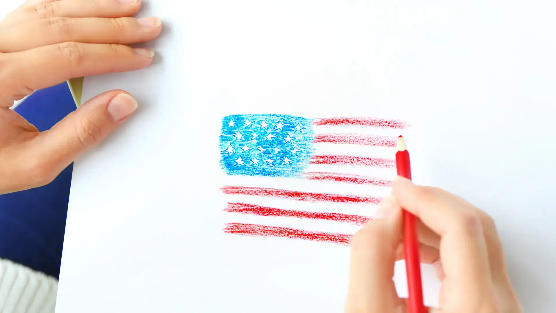 A hand drawing a flag using colored pencils