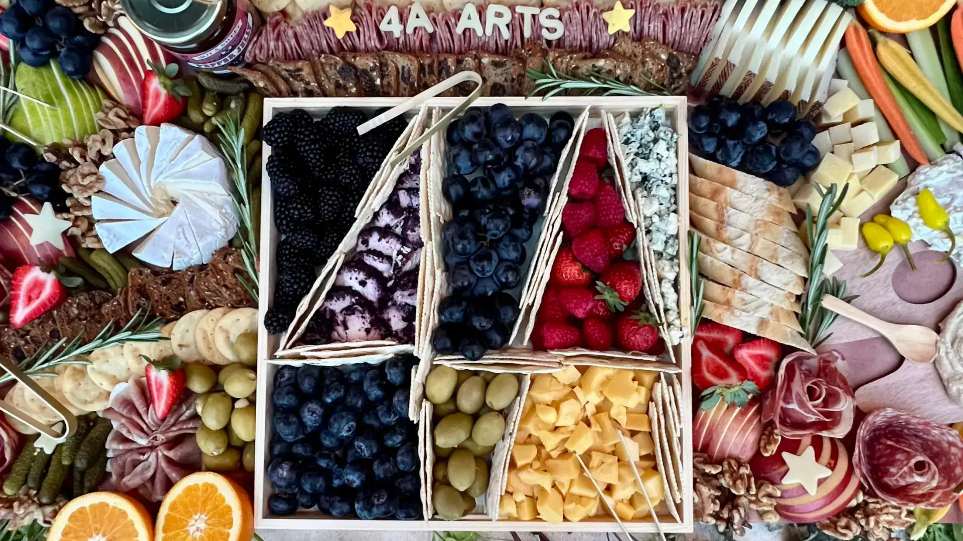A close up image of a charcuterie board in the shape of the 4A Arts logo