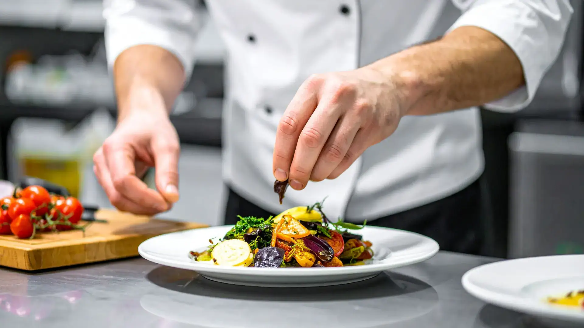 The hands of a chef are seen plating a meal