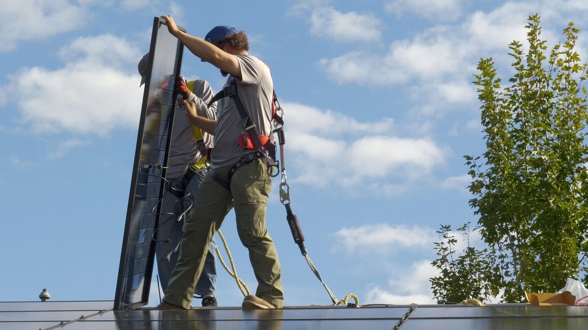 Two men on the roof of a home installing solar panels