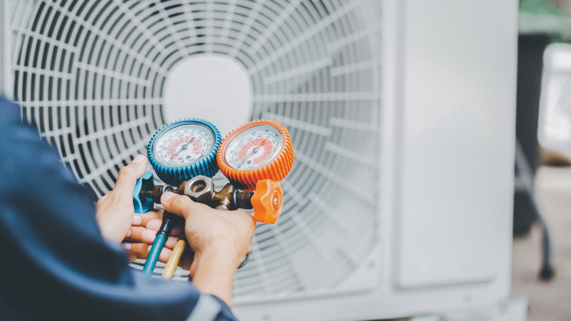 HVAC technician checking refrigerant pressure gauges on an outdoor air conditioning unit