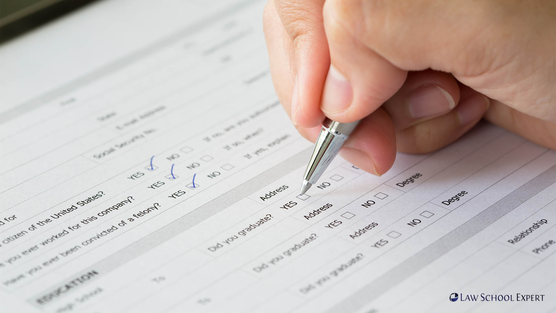 A person diligently completing a law school application form, emphasizing the importance of GPA and LSAT scores.