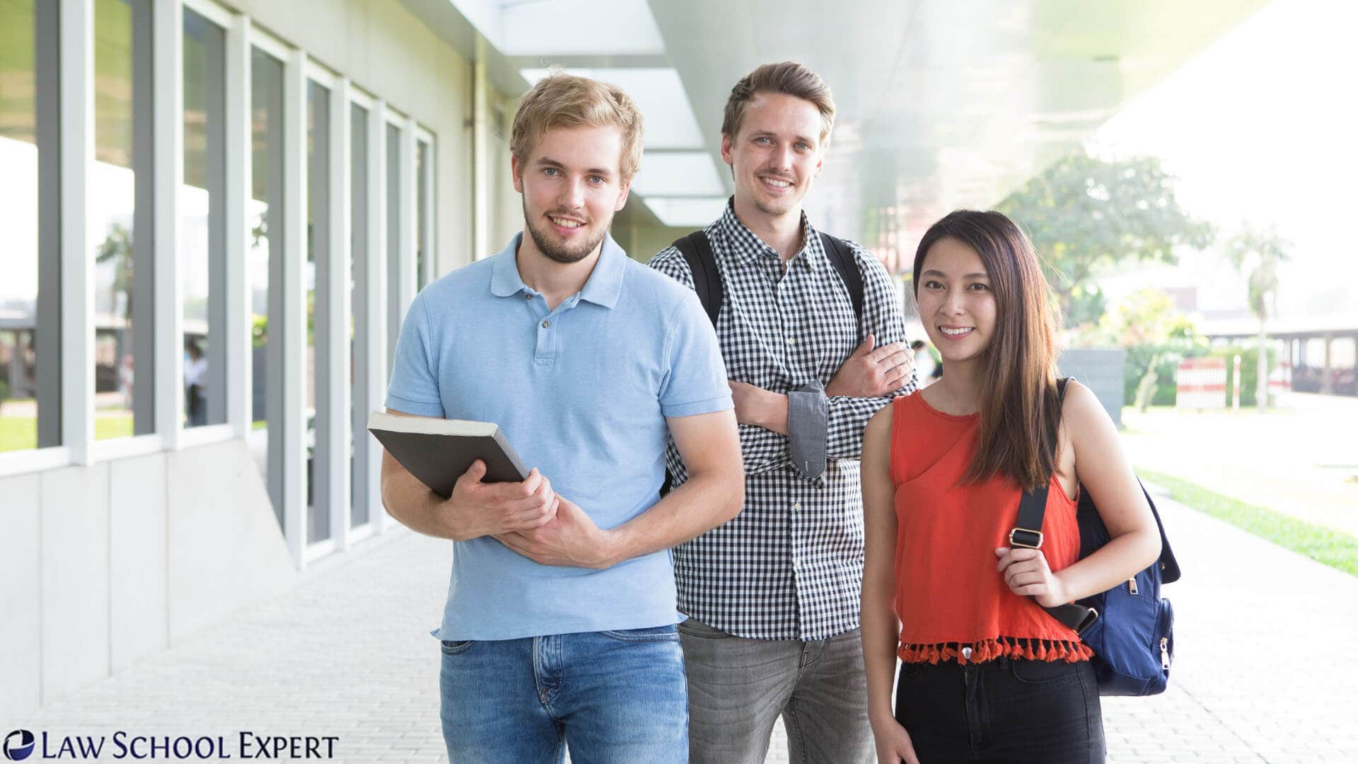 Three students stand in front of a law school building, discussing their aspirations for a career in law.