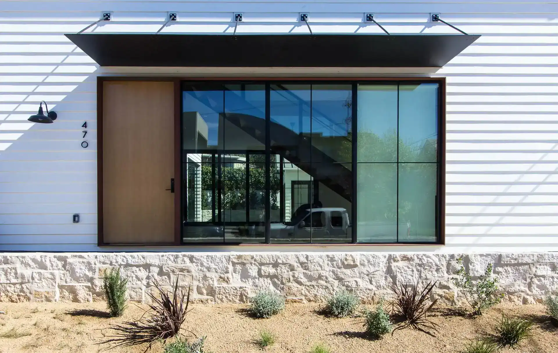 Modern minimalist house exterior with large glass window and wooden door.