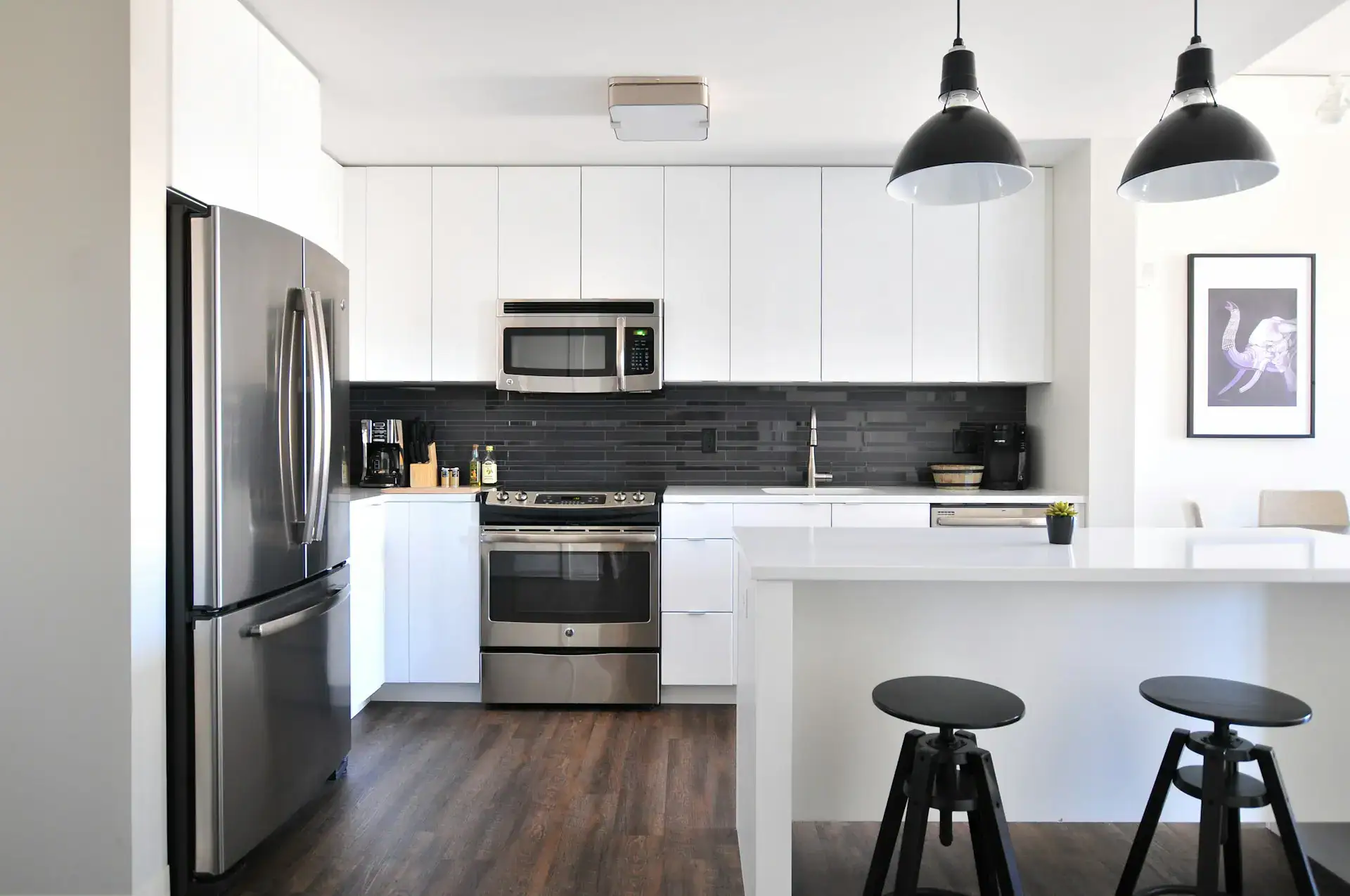 Modern kitchen design featuring white cabinetry, a dark tile backsplash, and stainless steel appliances showcasing 2026 kitchen remodeling trends.