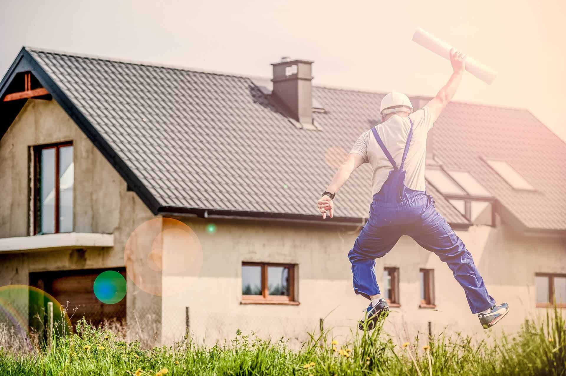 Image of a man with a tool in the right hand and of a house, with green grass in front