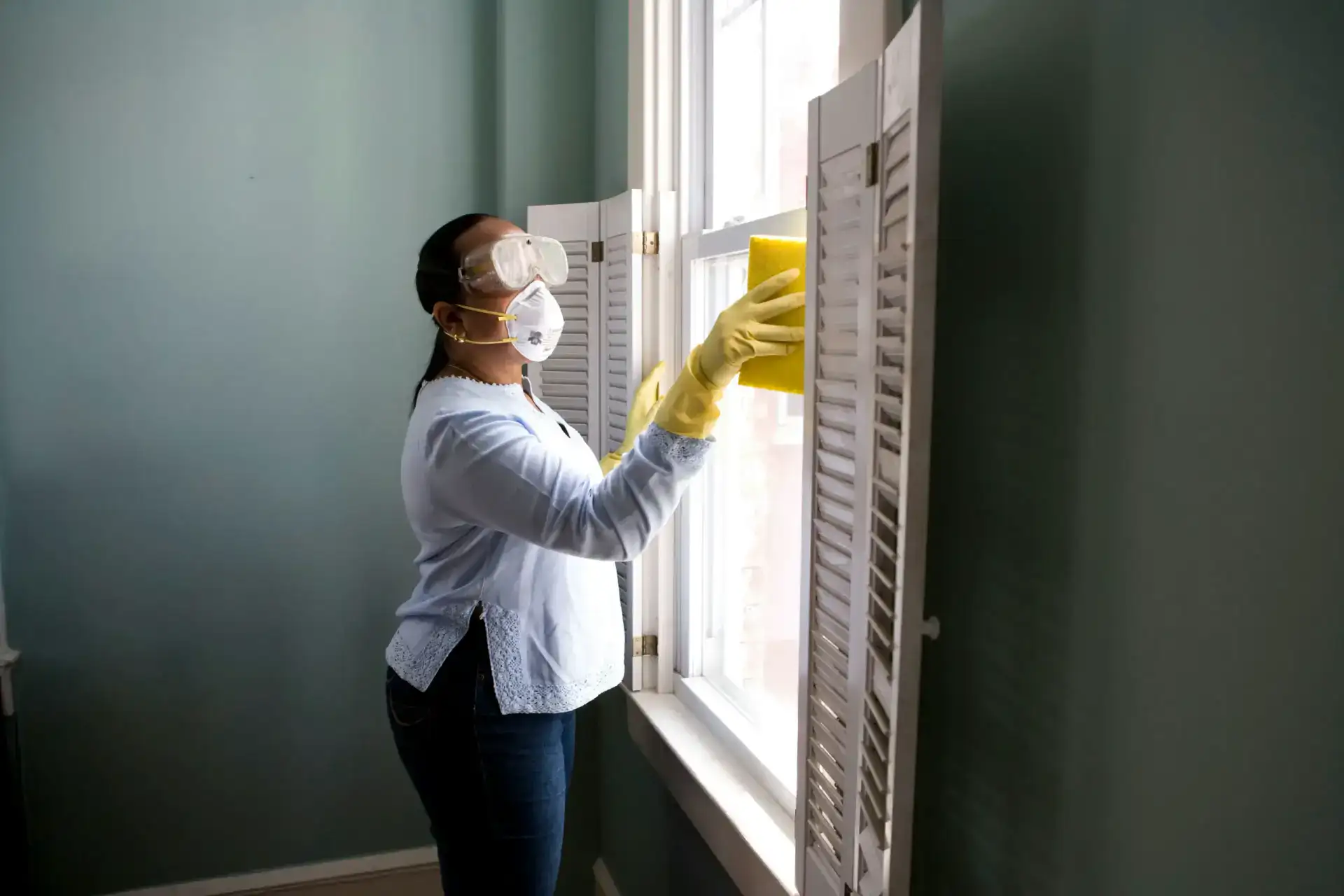 Professional house cleaner wiping interior windows during a residential cleaning service
