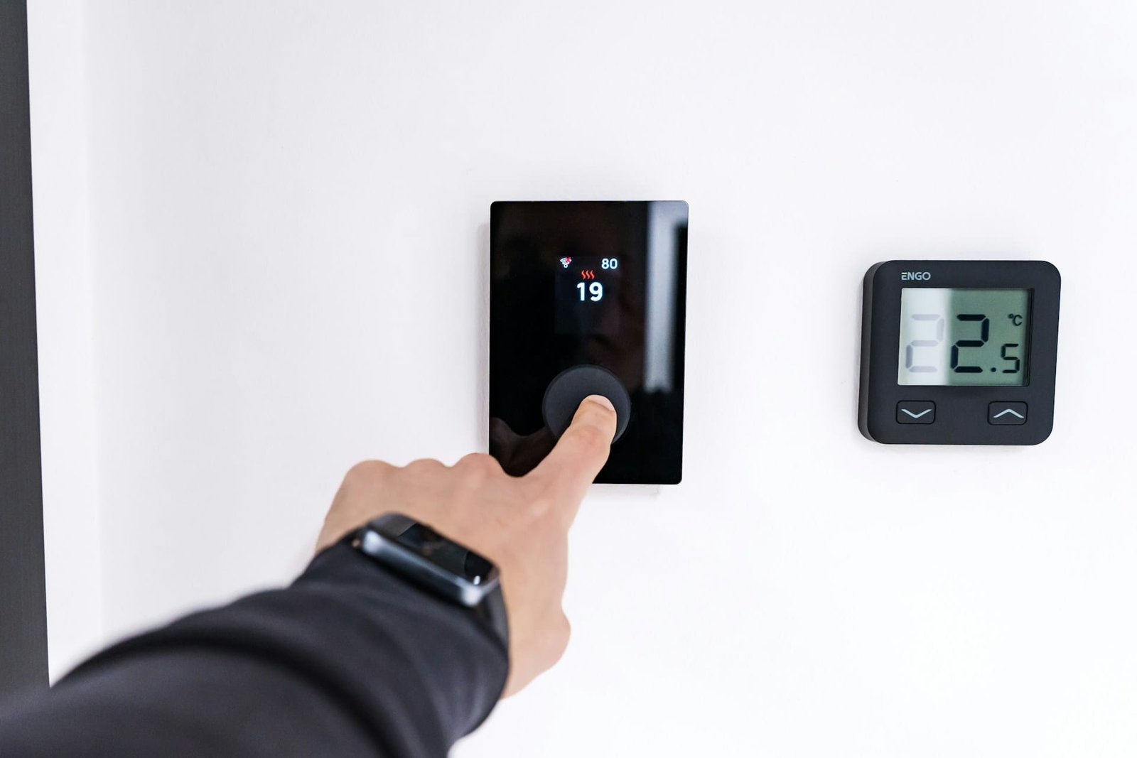 Hand touching a smart thermostat on a wall for smart home renovation trends 2026