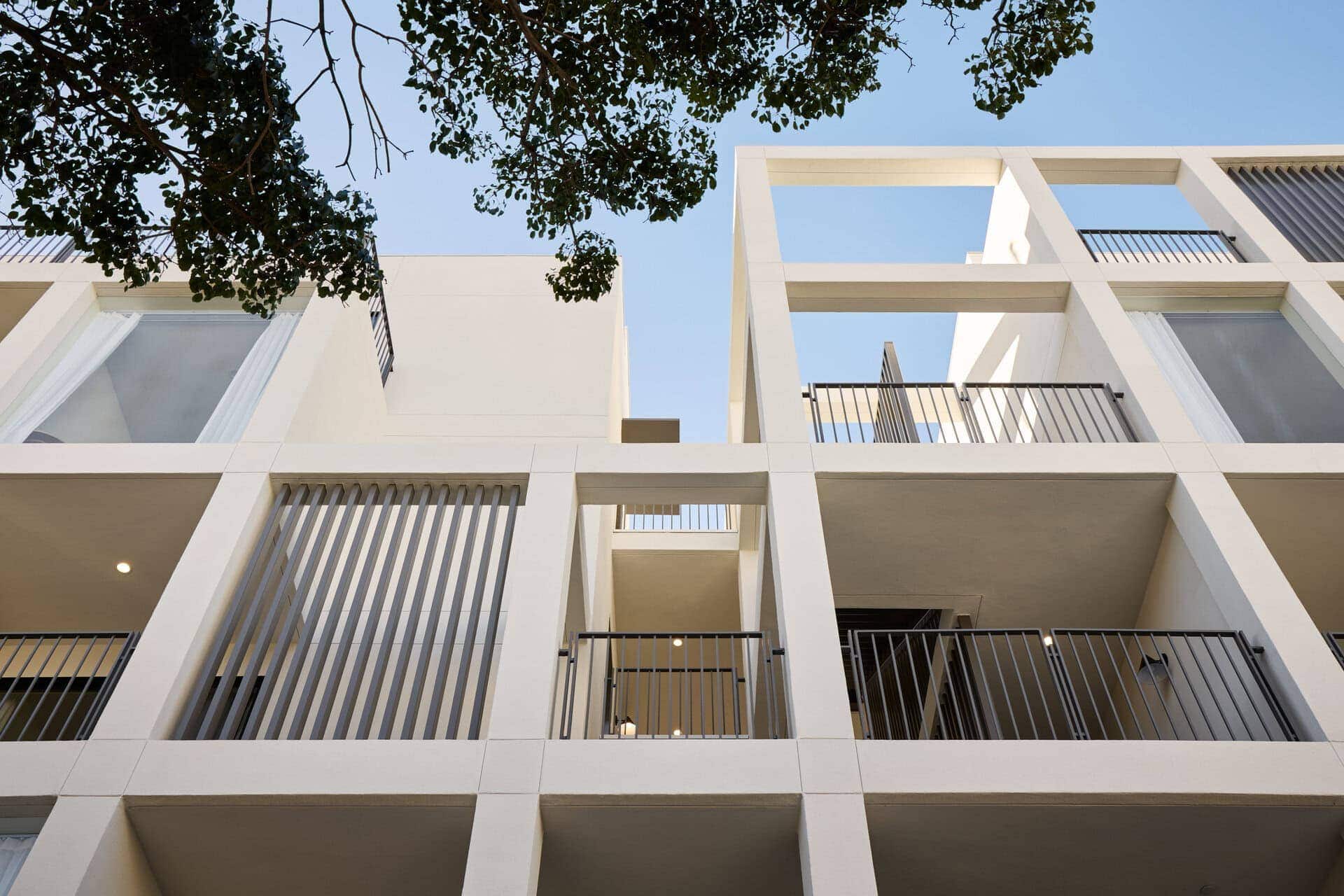 Modern white multi-story building with open balconies, clean lines, and minimalist design.