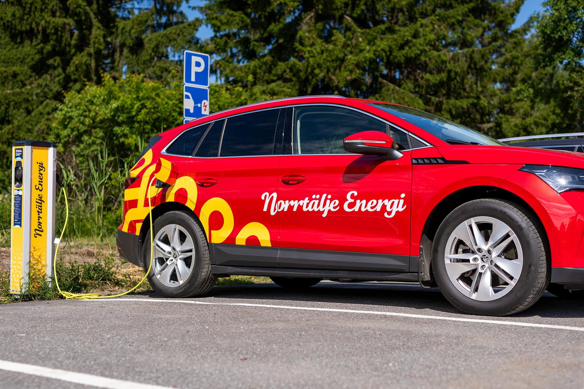 Elbil från Norrtälje Energi laddas vid laddstolpe märkt med Norrtälje Energis logotyp.