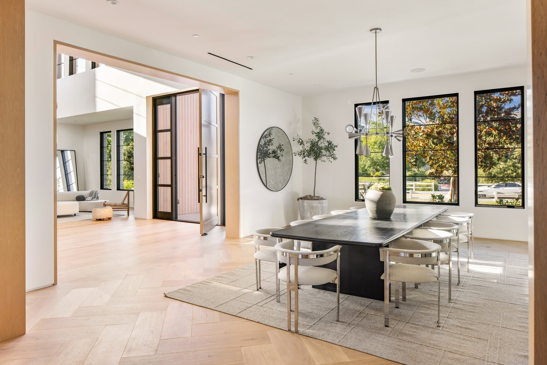 Open-concept dining room with large windows, minimalist decor, and modern lighting fixtures.