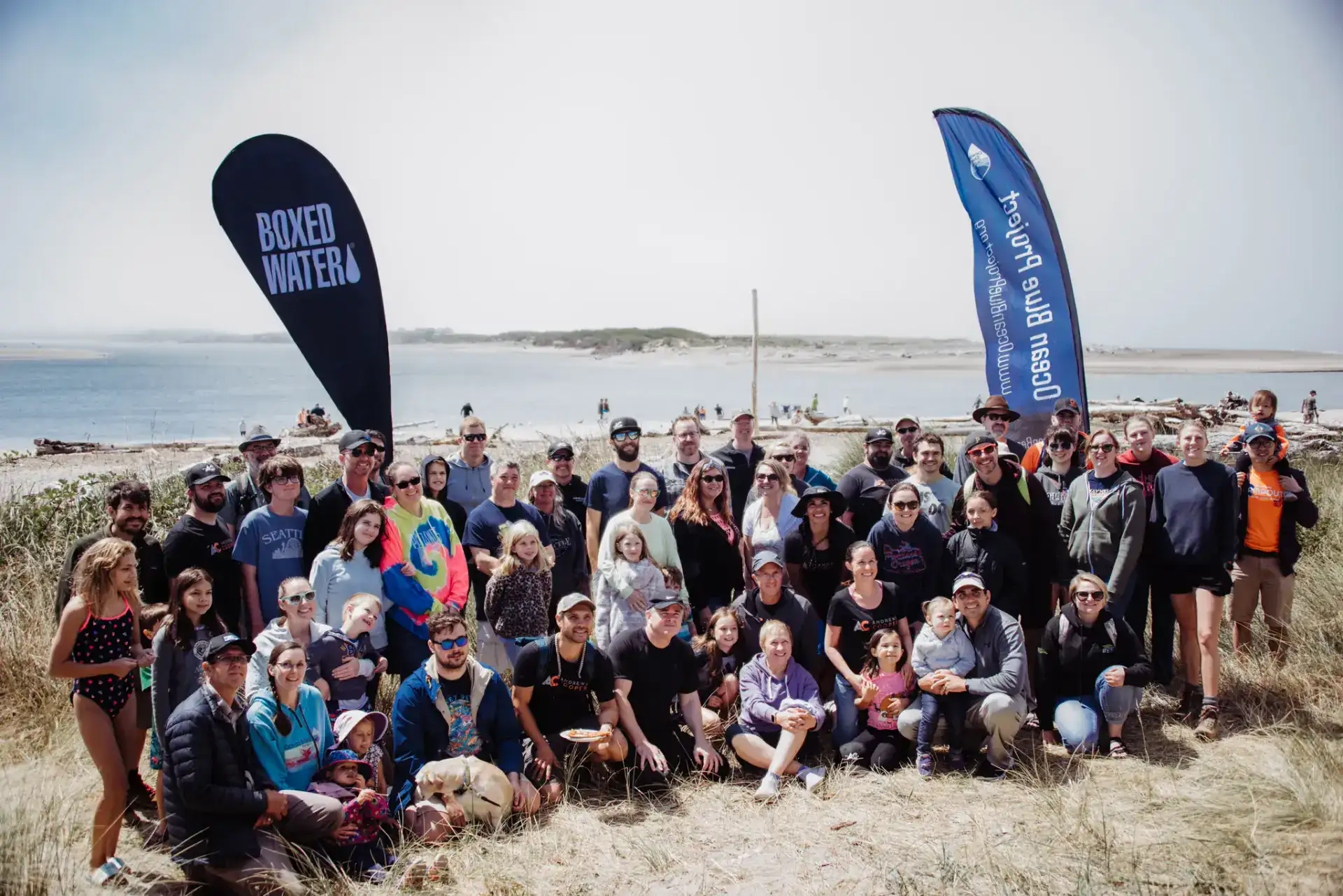 Large Ocean Blue Project cleanup crew group photos with Ocean Blue and Boxed Water flags at Lincoln City, Oregon beach.