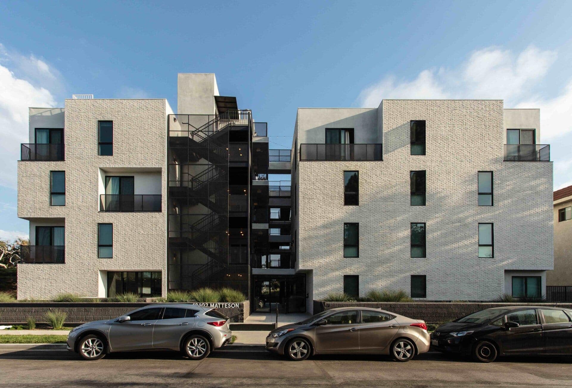 Contemporary residential apartment building with modern brick facade and black metal staircase exterior.