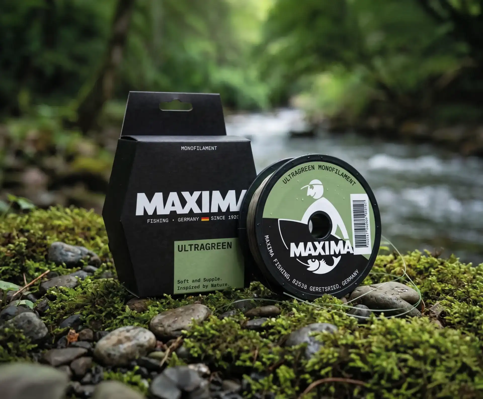 Maxima Ultragreen monofilament fishing line spool and box on mossy ground beside a forest stream