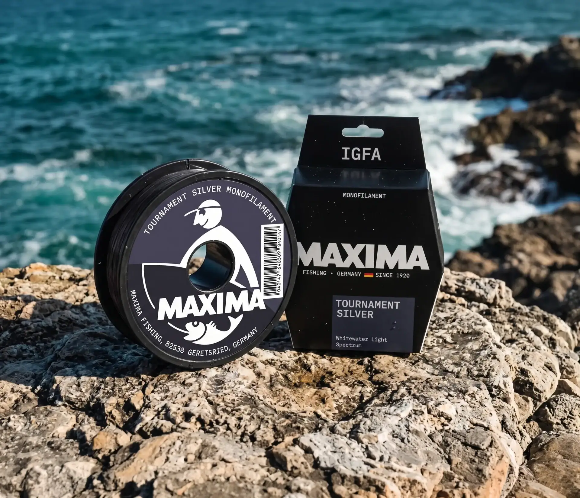 Maxima IGFA Tournament Silver monofilament fishing line spool and box on rocks by the sea