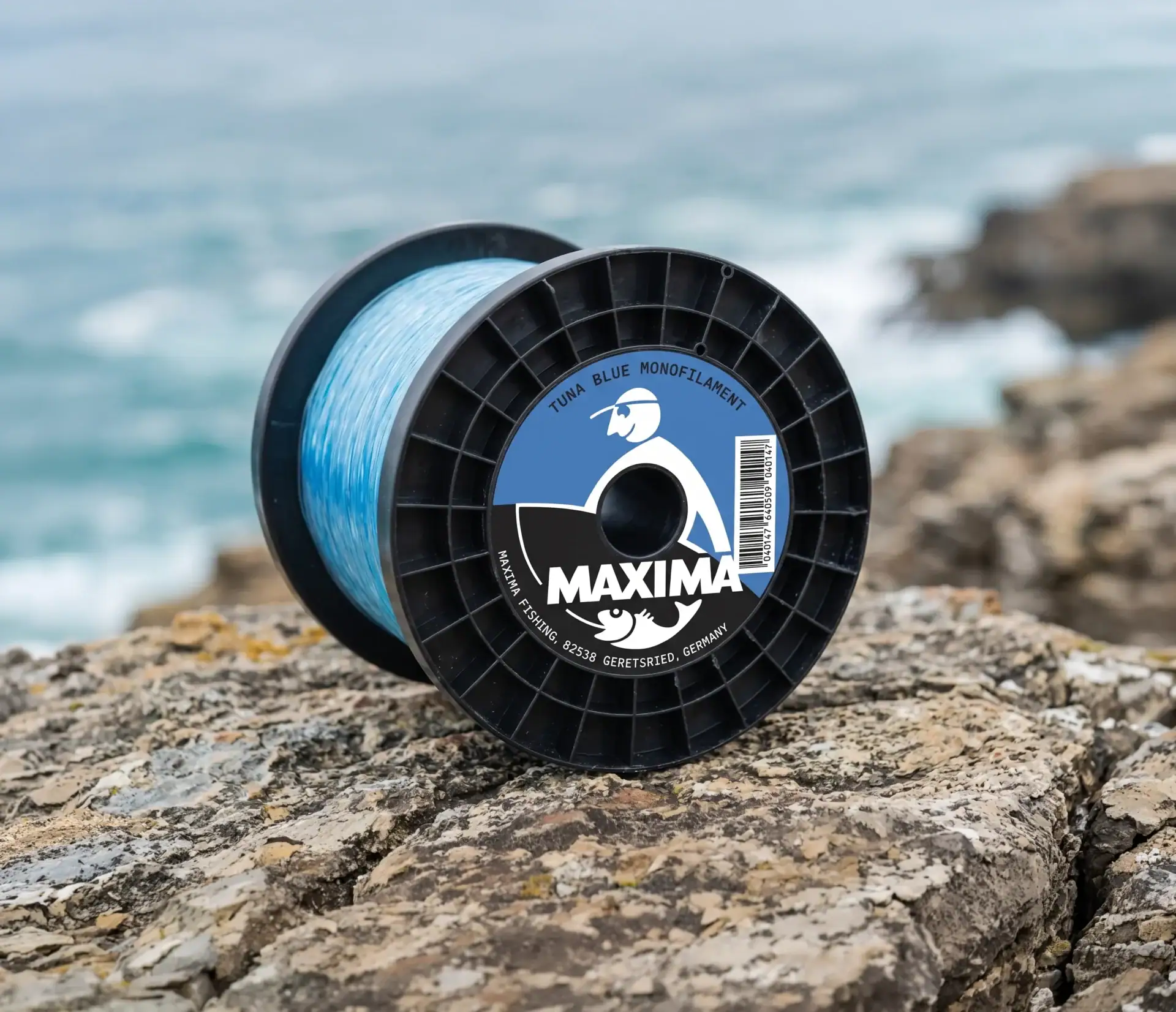 Large Maxima Tuna Blue monofilament bulk spool of blue fishing line on a rock by turquoise water