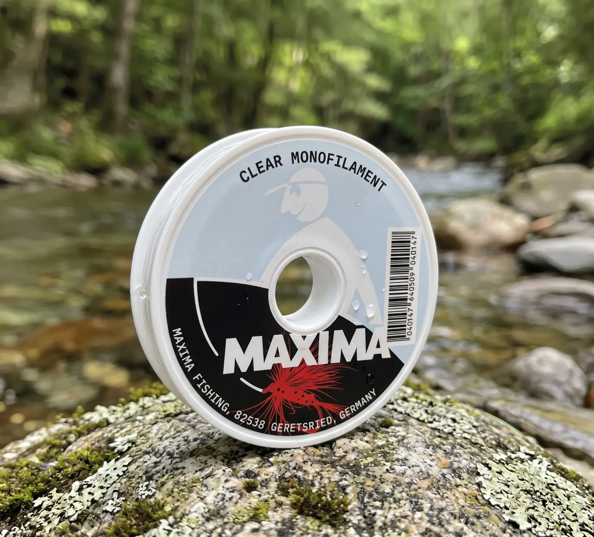 Maxima Clear fly fishing monofilament spool on a lichen-covered rock beside a mountain stream
