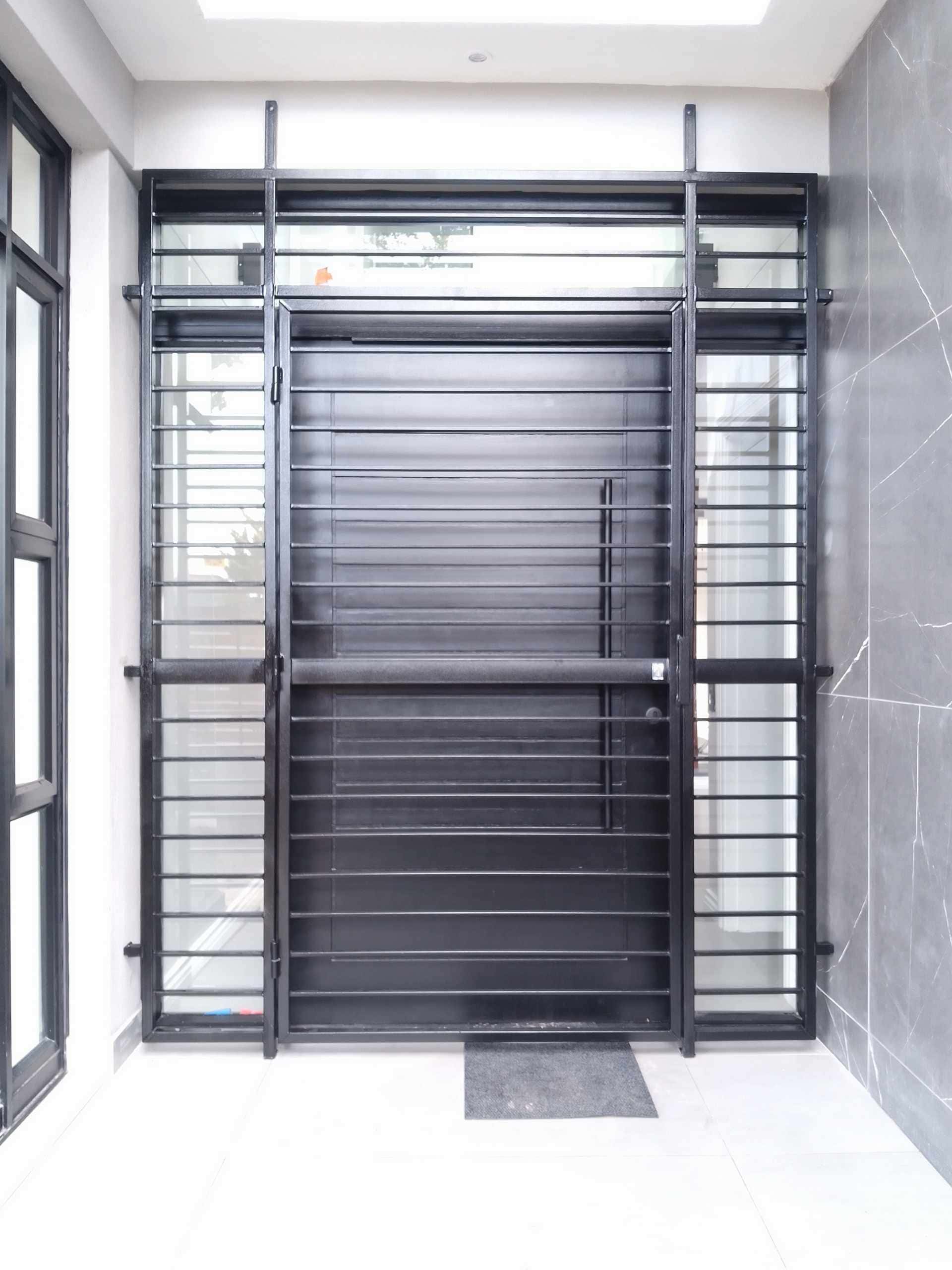 Modern matte-black horizontal-slat custom gates with glass sidelights securing a contemporary home entrance vestibule.