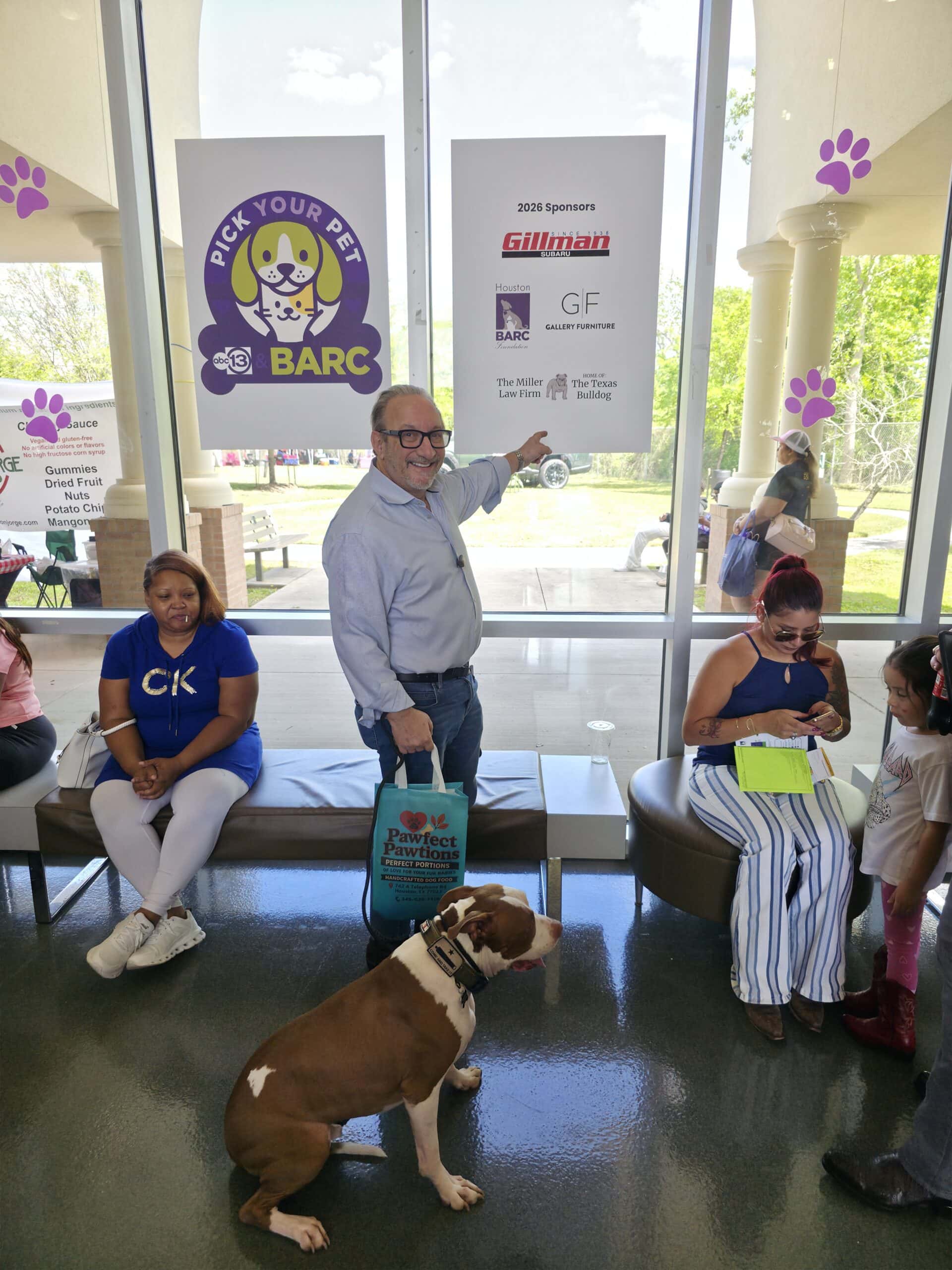 Adam Miller pointing to sponsor sign at BARC Houston adoption event