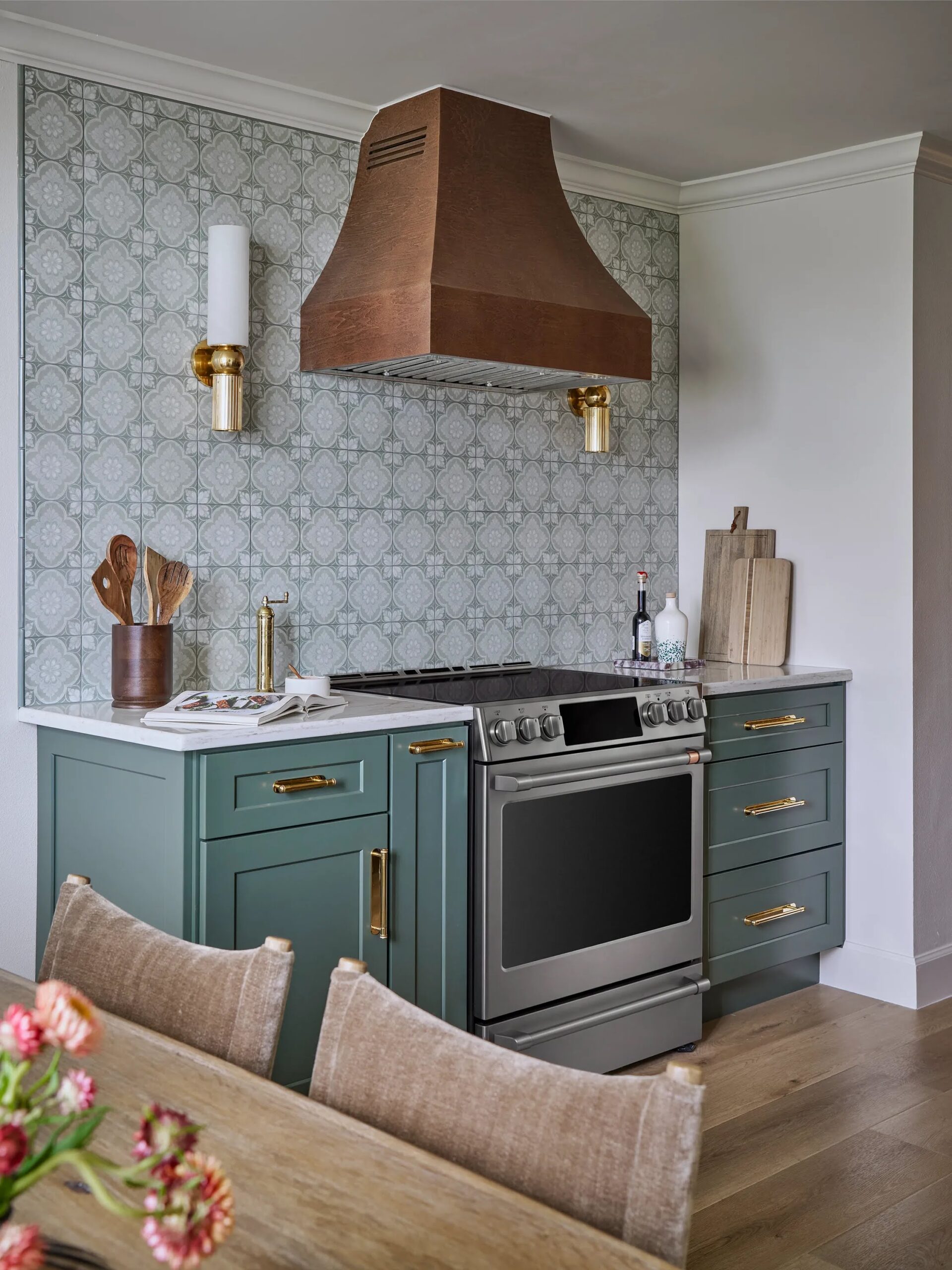 Kitchen with sage green cabinetry, patterned tile and a copper range hood by HLM Designs