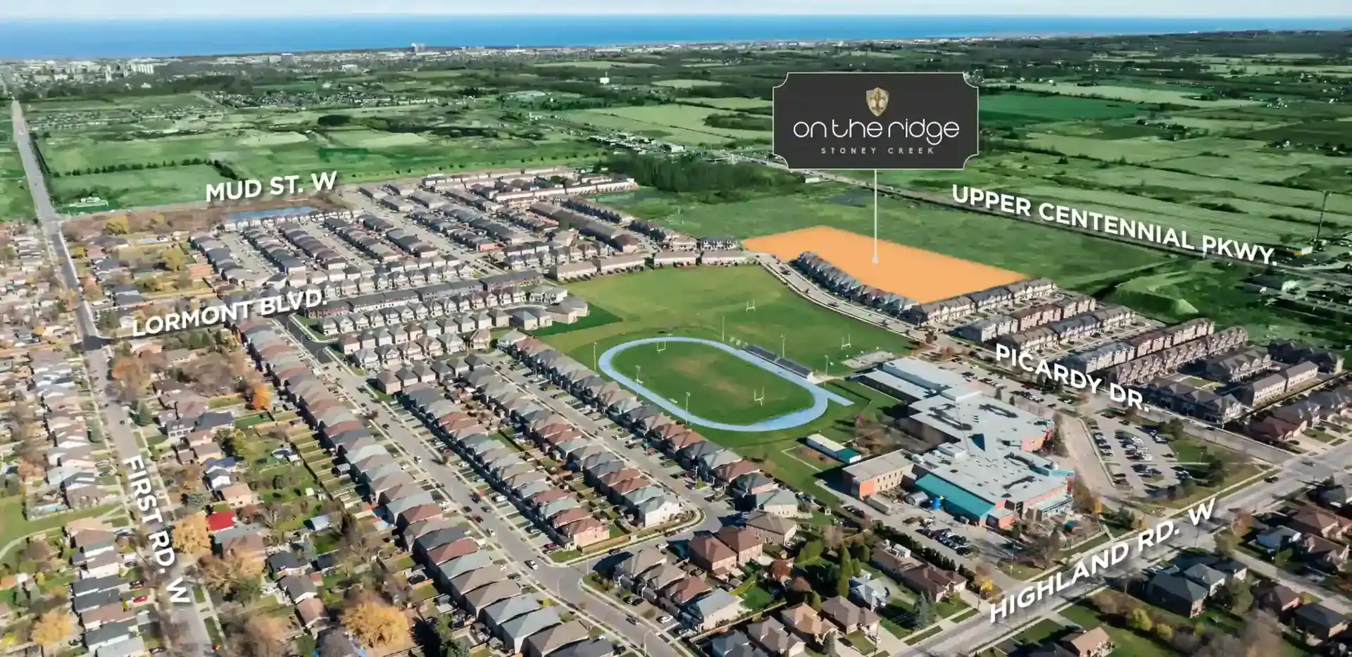 Aerial view of the On The Ridge community in Stoney Creek, showing the development site highlighted in orange near Upper Centennial Parkway and Highland Road West, adjacent to a local school and athletic track.