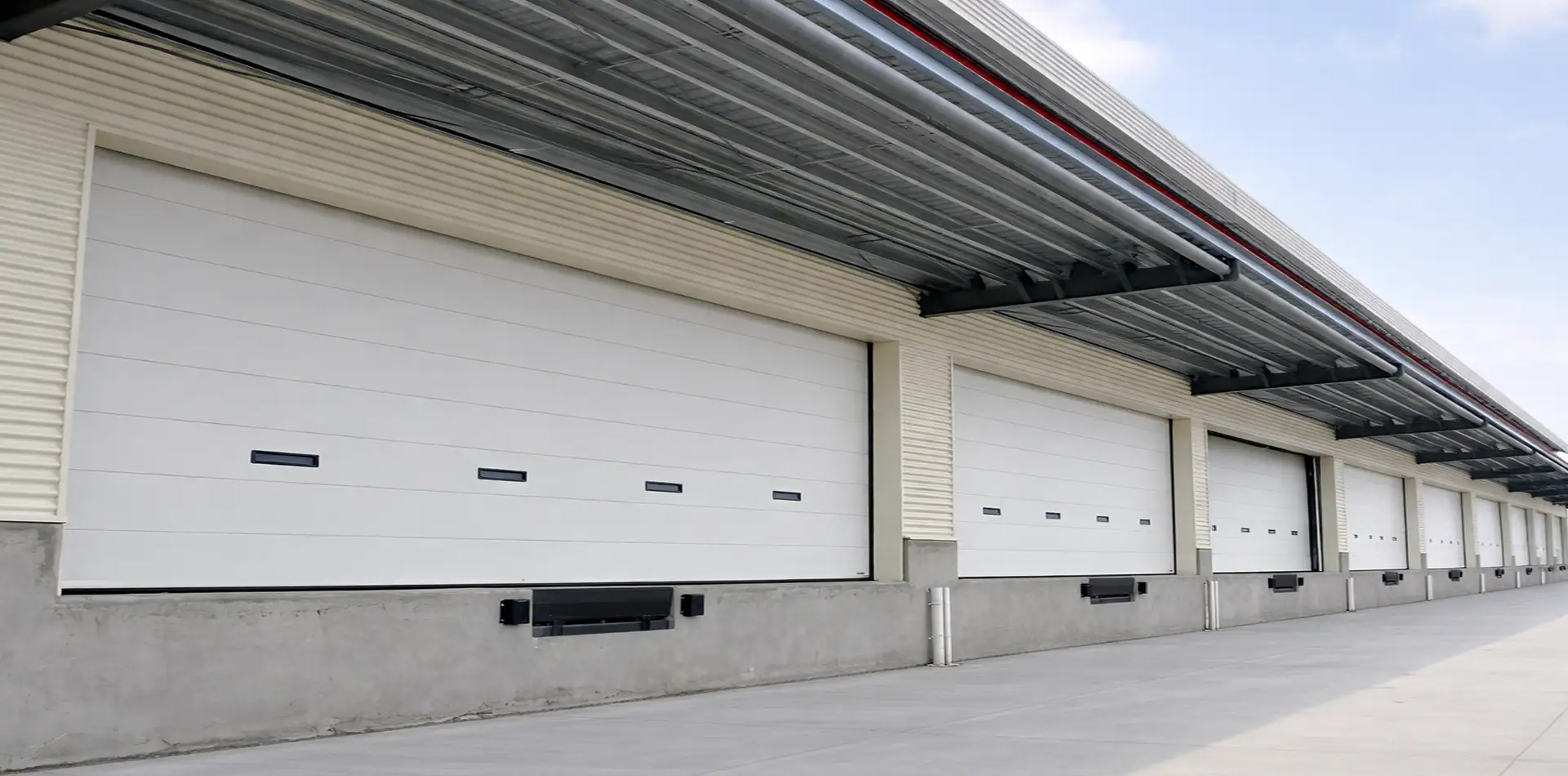 Modern logistics warehouse sectional door featuring vision panels, operating alongside a hydraulic dock leveler for high-volume distribution.