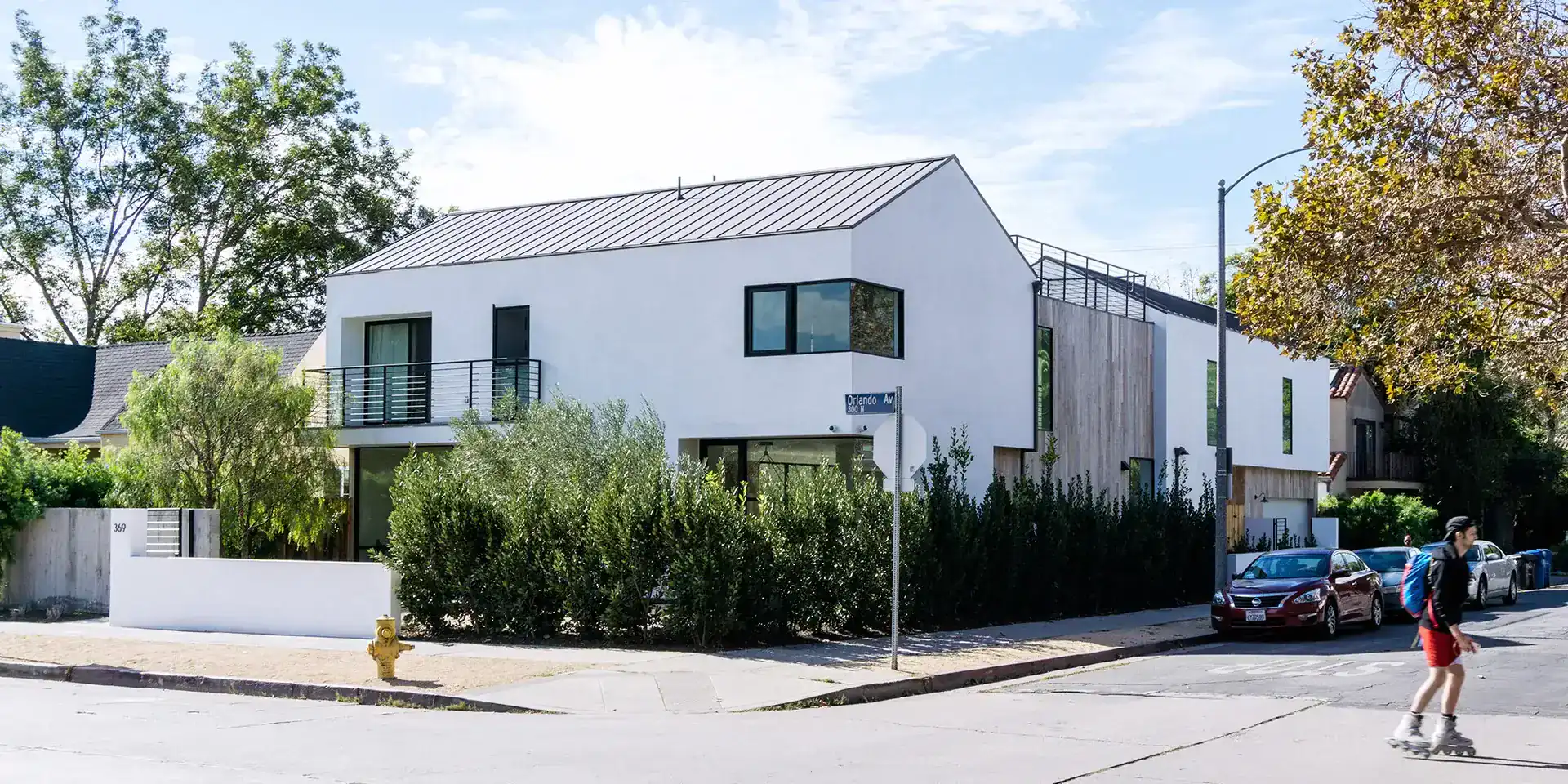 Contemporary white stucco residential building with clean lines, large windows, and flat and gabled roof sections.
