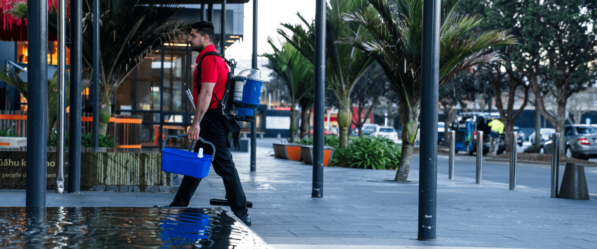 An AMC team member walking through a shopping centre in the early morning, carrying professional cleaning equipment before retail stores open.