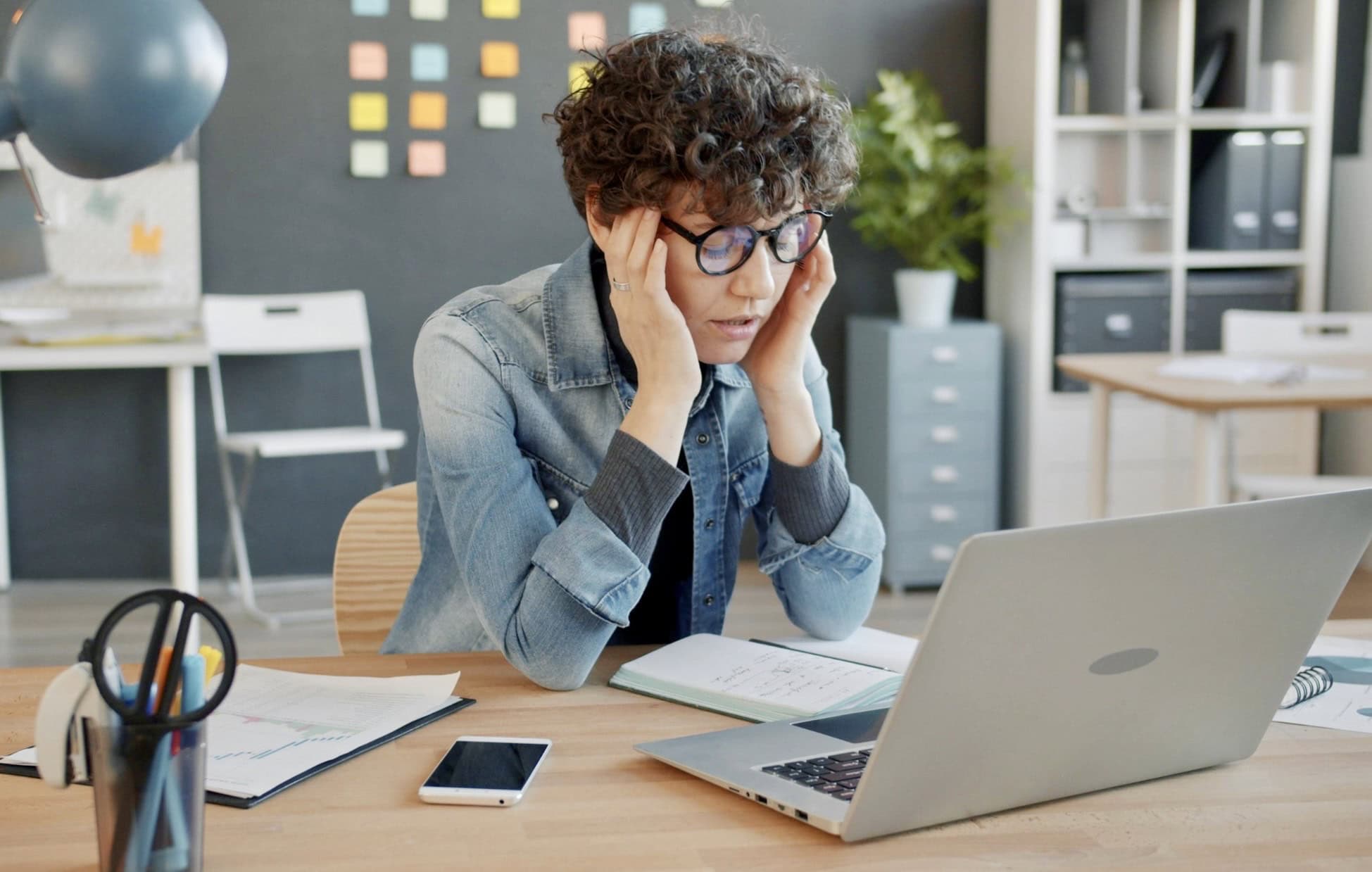 Woman looking overwhelmed at her laptop, illustrating ADHD task paralysis and difficulty starting tasks.
